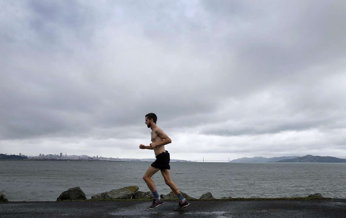 A hearty jogger runs along the shoreline at Cesar Chavez Park in Berkeley, Calif. on Saturday, March 5, 2016 shortly before the first of a series of major rainstorms drenches the Bay Area.