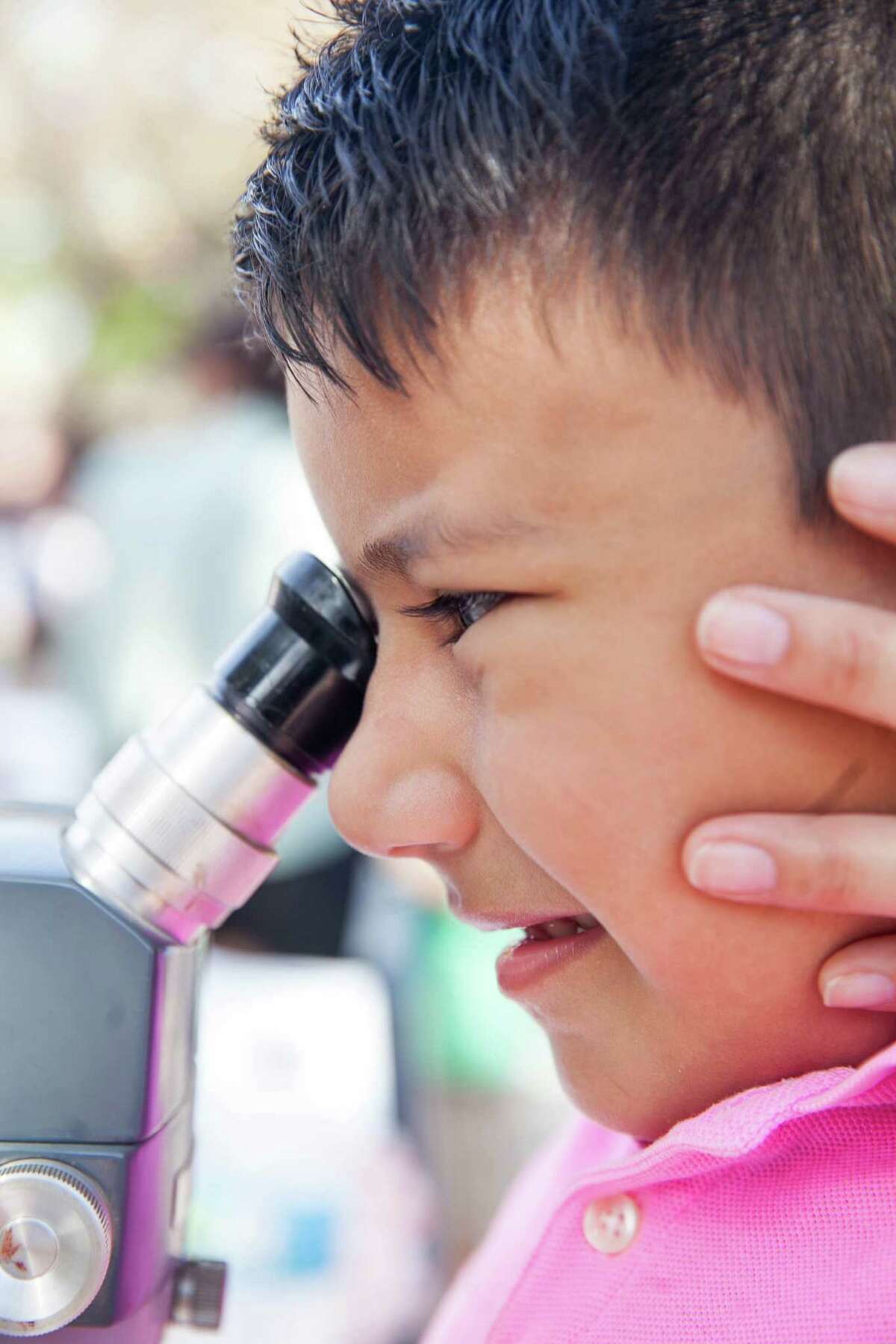Giovanni Garcia, 5, has some help from his godmother as he tries to view an ant through a microscope at the Sigma XI, The Scientific Research Society stand Saturday March 5, 2015 during the 2016 Science Fiesta, organized by the UT Health Science Center at La Villita.