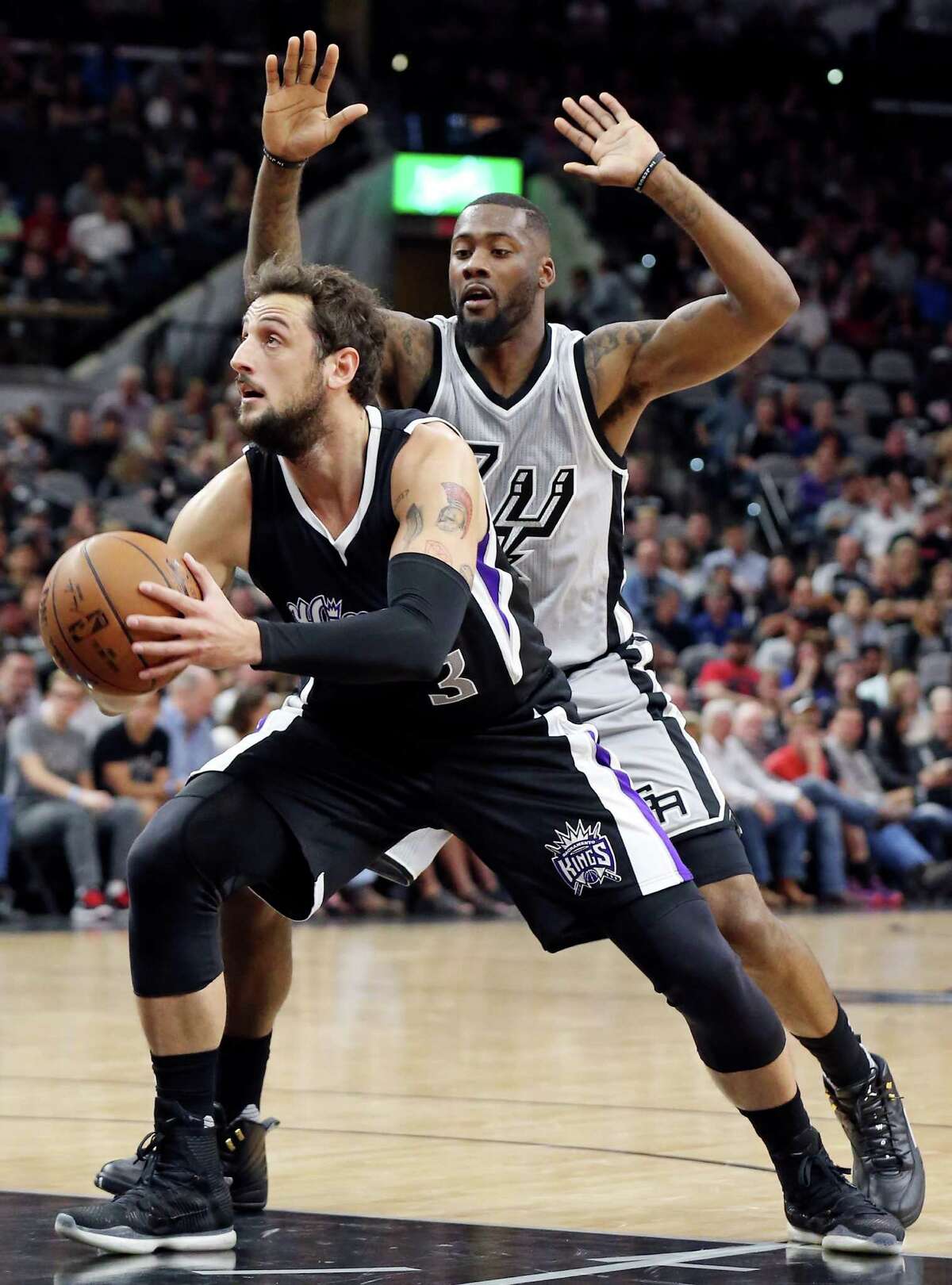 Sacramento Kings' Marco Belinelli looks for room around San Antonio Spurs' Jonathon Simmons during first half action Saturday March 5, 2016 at the AT&T Center.