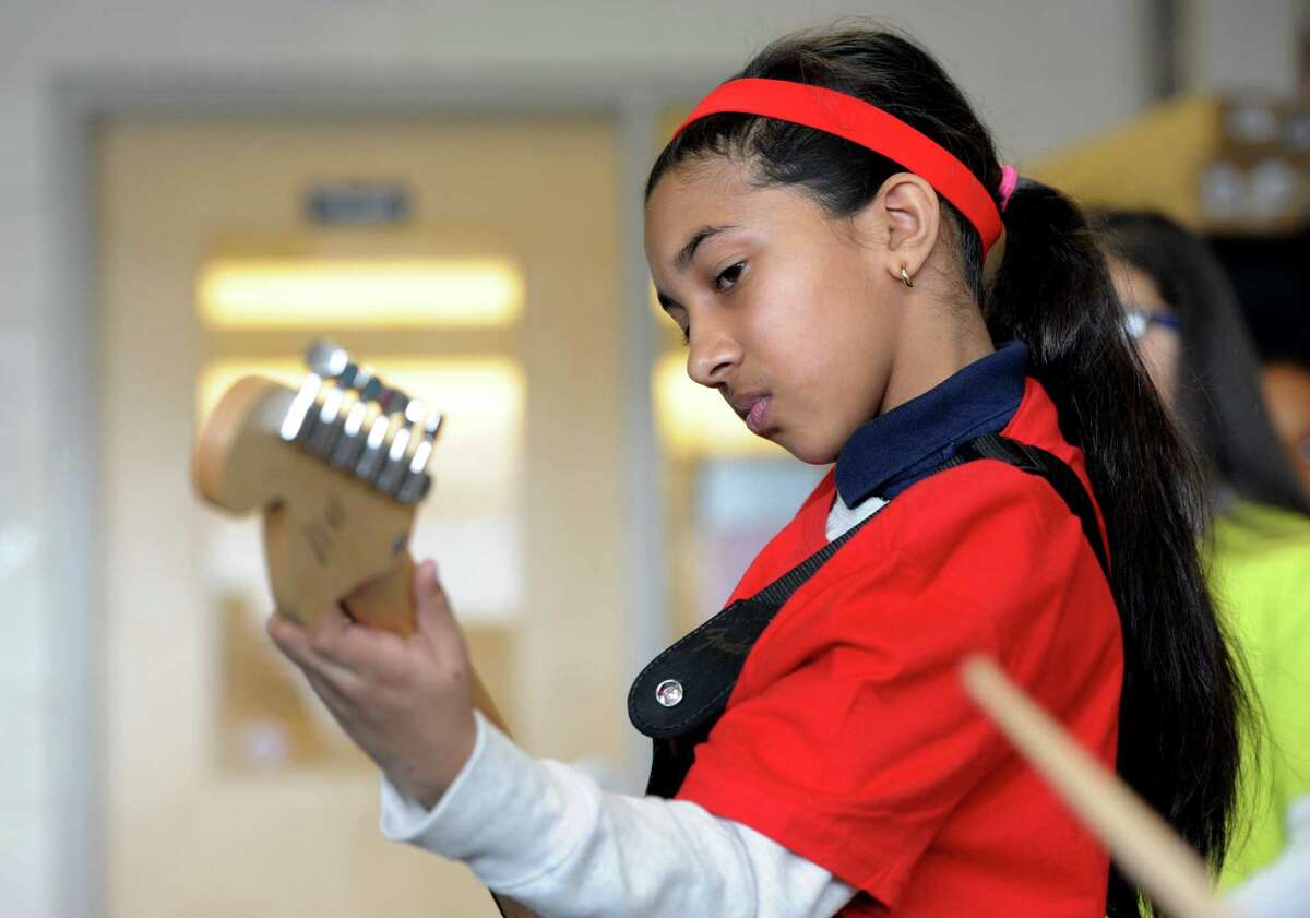 Tisdale School student Lindsey Mohammed plays a little guitar with musician and former New York Yankee, Bernie Williams plays guitar at the school in Bridgeport, Conn. on Monday, March 7, 2016. Williams mentors the students as part of the national Turnaround Arts program that empowers high-need schools with arts resources, training and arts integration into other subject areas.