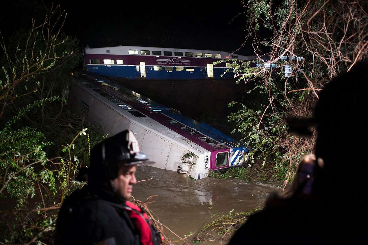 An ACE commuter train rests partially submerged in a creek following a derailment on Monday, March 7, 2016, in Sunol, Calif.