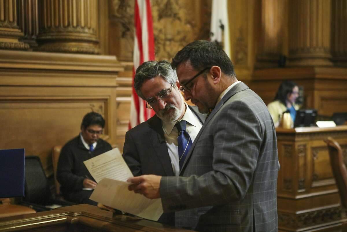 Supervisor Aaron Peskin looks over paperwork with Supervisor David Campos during a Board of Supervisors meeting at City Hall in San Francisco.