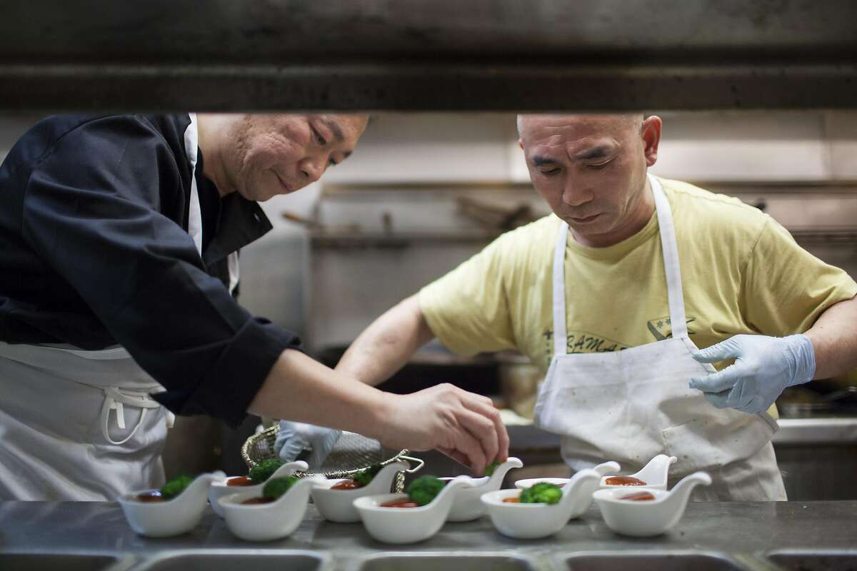 Chili House owner Li Jun Han (left) puts the finishing touches on pork belly braised Hangzhou-style, which is one of the Forbidden City banquet dishes at Chili House in San Francisco.