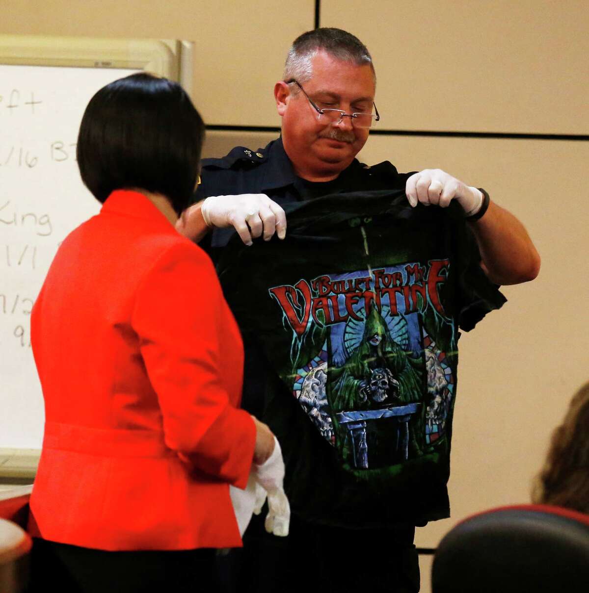 San Antonio Police Sgt. Ricky David Lopez (center) holds up a shirt belonging to murder victim Daniel Lee Cantu during questioning from prosecutor Kimberly Gonzalez during the Anthony Lee Smith murder trial in the 186th State District Court with Judge Jefferson Moore presiding on Thursday, Mar. 10, 2016. Smith is alleged to have shot Cantu and the shirt appeared to be marked with yellow-dashed lines to indicate the entry point of the bullet wound. (Kin Man Hui/San Antonio Express-News)
