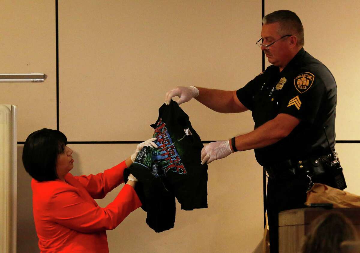 San Antonio Police Sgt. Ricky David Lopez (right) holds up a shirt belonging to murder victim Daniel Lee Cantu during questioning from prosecutor Kimberly Gonzalez (left) during the Anthony Lee Smith murder trial in the 186th State District Court with Judge Jefferson Moore presiding on Thursday, Mar. 10, 2016. Smith is alleged to have shot Cantu and the shirt is marked with yellow-dashed lines to indicate the entry point of the bullet wound. (Kin Man Hui/San Antonio Express-News)