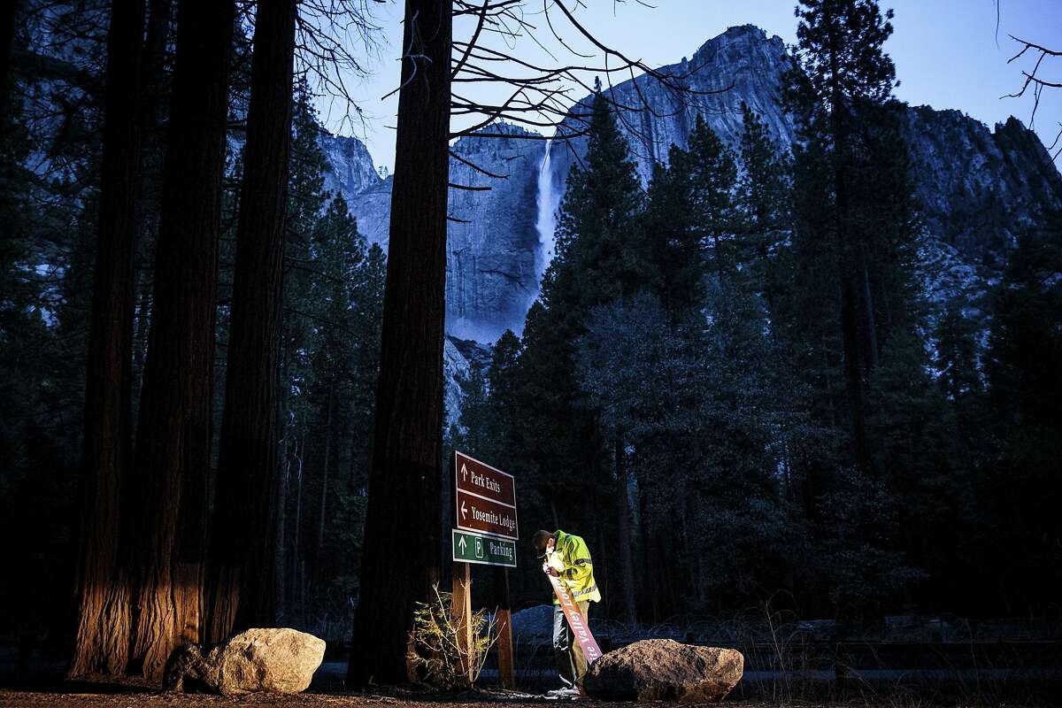 Josh Alsup, a park service mechanic, works to cover a Yosemite Lodge road sign with one that reads Yosemite Valley Lodge, at Yosemite National Park in California, March 1, 2016. Delaware North, a company that until recently ran the park�s hotels, restaurants and shops, has caused an uproar by having apparently successfully trademarked the name Yosemite National Park. (Max Whittaker/The New York Times)
