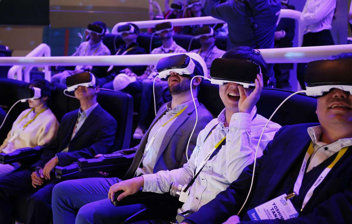 FILE - In this Jan. 6, 2016 file photo, people react as they wear Samsung Gear VR goggles at CES International in Las Vegas. VR is a habitat of countless possibilities, an exhilarating refuge that yanks one from the sidelines and thrusts them into the action. (AP Photo/John Locher, File)