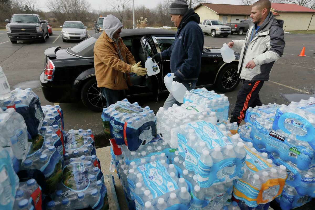 Volunteers load a vehicle with bottled water at Our Lady of Guadalupe Church, Friday, Feb. 5, 2016 in Flint, Mich. Michigan Gov. Rick Snyder is defending how his office responded to an email flagging a potential link between a surge in Legionnaires' disease and Flint's water. (AP Photo/Carlos Osorio)