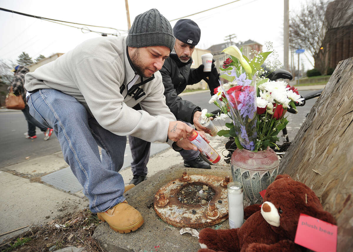 Neighborhood residents Sammy Negron, left, and Victor Nazario light candles on a small memorial to Carmen Martinez, who was struck and killed by a pickup truck while crossing John Street, near the location of the accident in Bridgeport, Conn. on Tuesday, January 12, 2016.