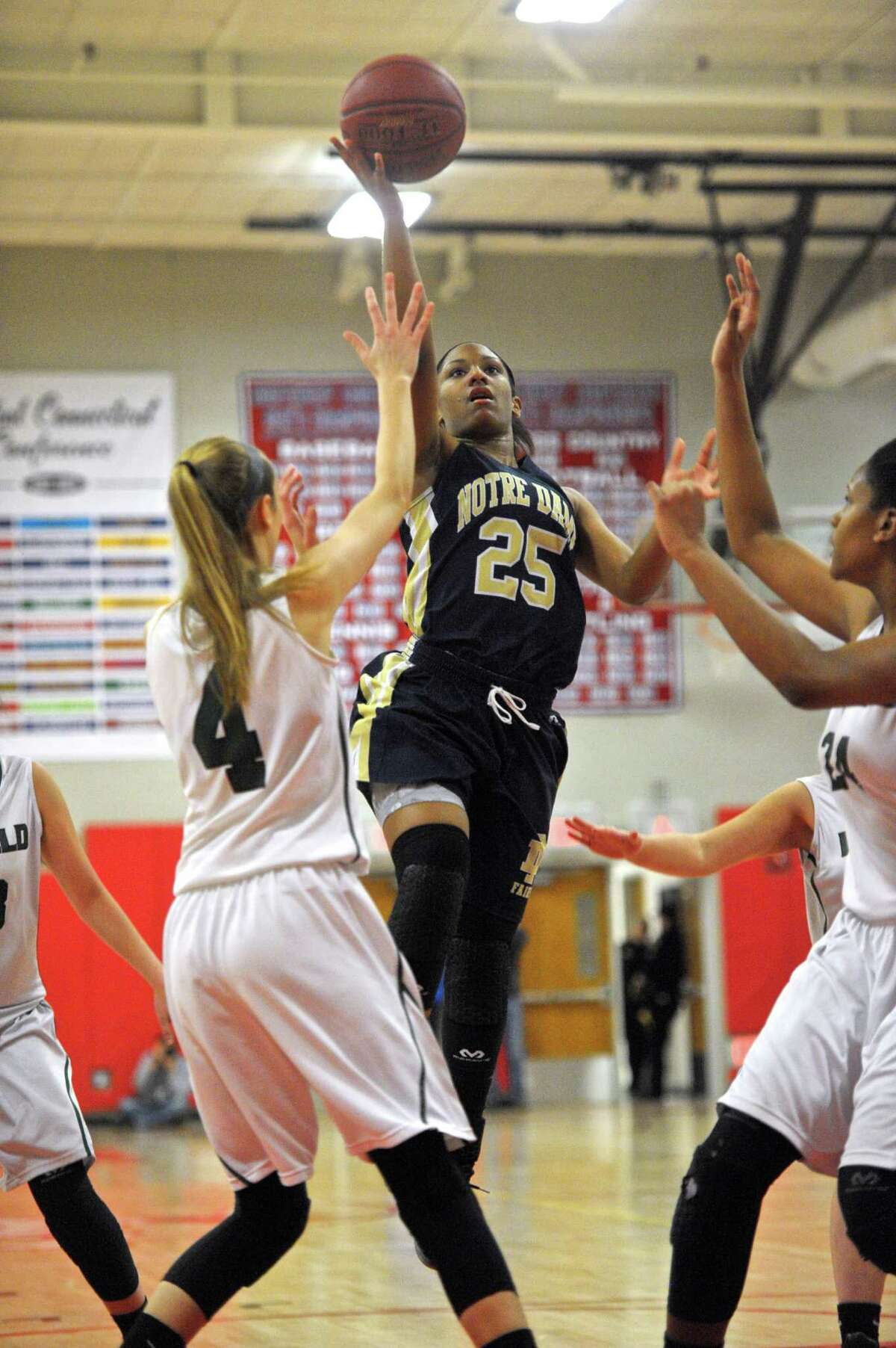 Notre Dame-Fairfield's Dayniera Artis (25) drives to the basket between Enfield's Erica Lovering (4) and Mary Baskerville (24) in the Connecticut Class-M girls semifinal basketball game between Notre Dame-Fairfield and Enfield high schools, on Friday night, March 11, 2016, at Berlin High School, Berlin, Conn.