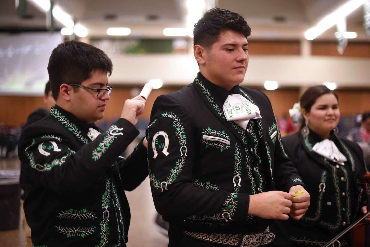 Cameron Hinojosa, left, uses a lint remover on the mariachi outfit of Manuel Valles prior to first-ever Mariachi State Festival at Southwest High School on Saturday, March 12, 2016. More than 40 groups from around the state competed in the two-day event. They are members of the Southwest High School Mariachi Los Dragones.