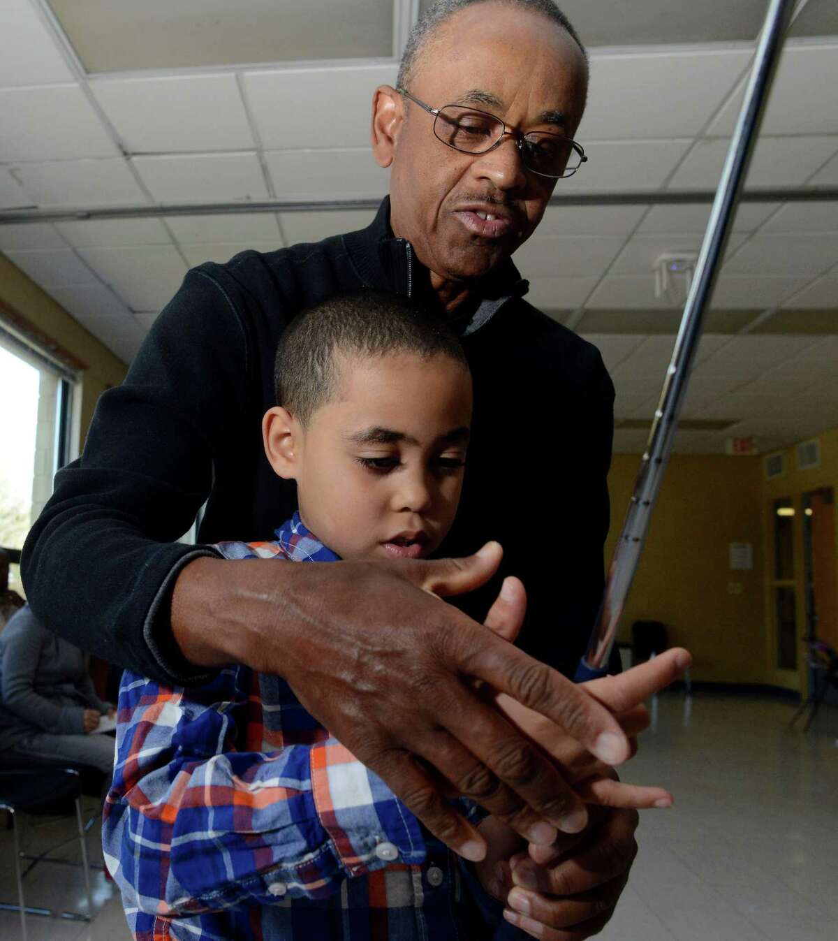 Mentor Duane Hill works with Yaniel Pascual on the proper way to grip a club during the 100 Youth Golf program at the Addison Community Center in Stamford, Conn on March 13, 2016. This is the fourth time the youth golf program has been offeded and run by the 100 Black Men of Stamford, an organization that mentors African-American and Latino teens.