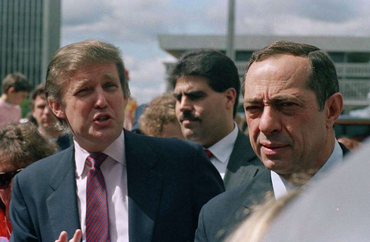 Developer Donald Trump and New York State Gov. Mario Cuomo get together before the start of the Tour De Trump bicycle race in Albany, New York on May 6, 1989. (AP Photo/Alan Soloman)