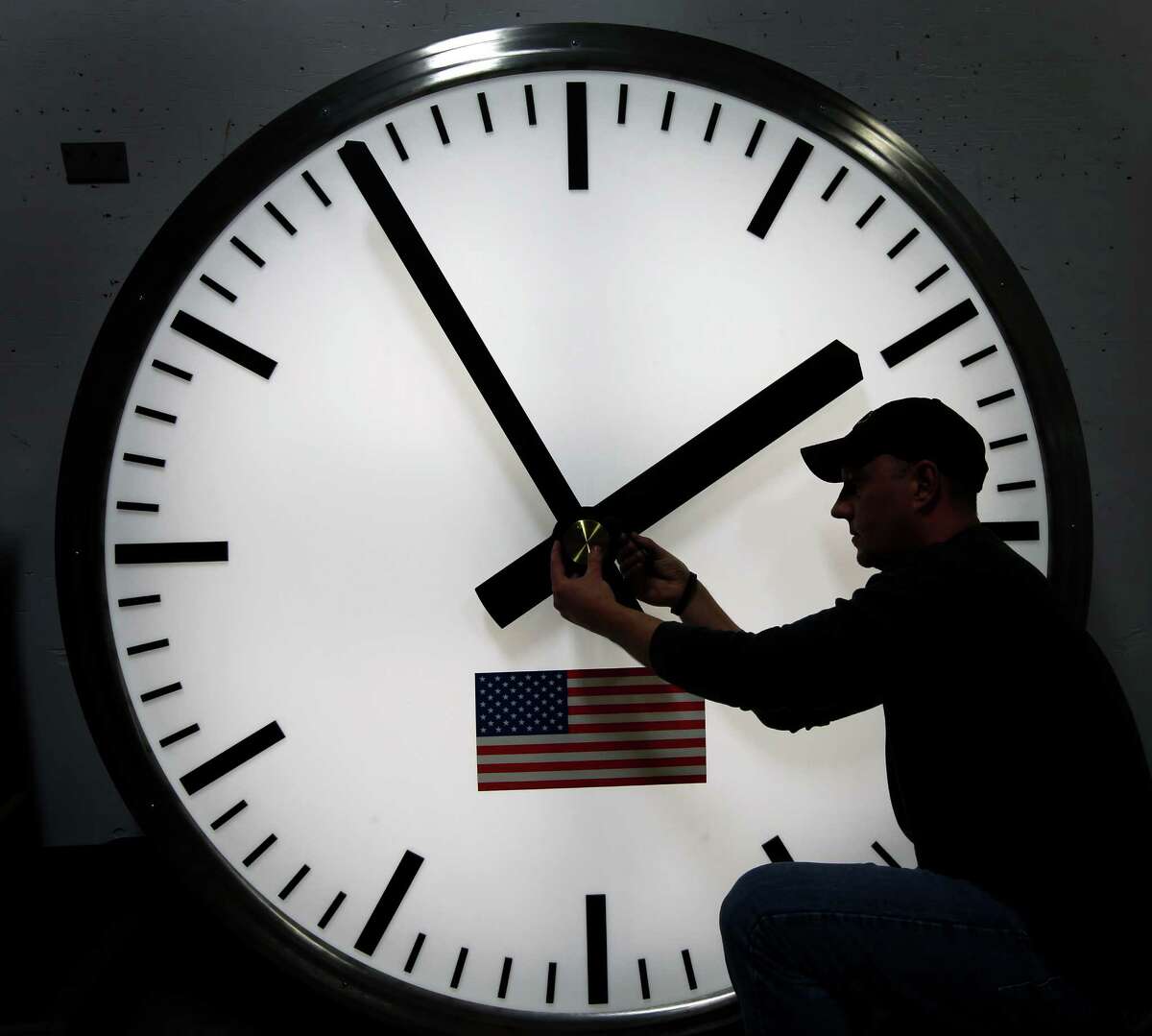 Dave LeMote uses an allen wrench to adjust hands on a stainless steel tower clock at Electric Time Company, Inc. in Medfield, Mass., Friday, March 7, 2014. Most Americans will set their clocks 60 minutes forward before heading to bed Saturday night, but daylight saving time officially starts Sunday at 2 a.m. local time (0700GMT). (AP Photo/Elise Amendola)