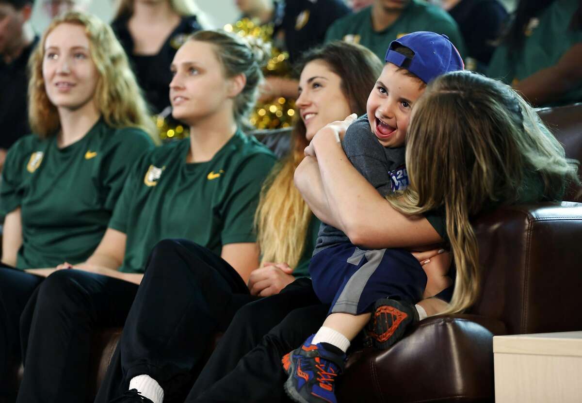 Ari Greenfield, 4, gets held by his babysitter and USF Women's Basketball player Taylor Proctor during a viewing party for the NCAA Women's Basketball tournament seeding at War Memorial at the Sobrato Center at USF in San Francisco, California, on Monday, March 14, 2016.