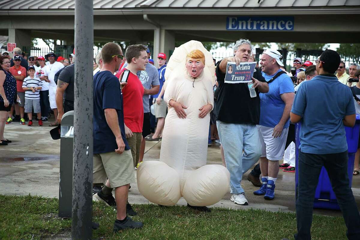 A person dressed as a phallic symbol and wearing a Donald Trump mask is seen as people wait to enter a rally for Republican presidential candidate Donald Trump at the Sunset Cove Amphitheater on March 13, 2016 in Boca Raton, Florida. Mr. Trump continues to campaign before the March 15th Florida primary.