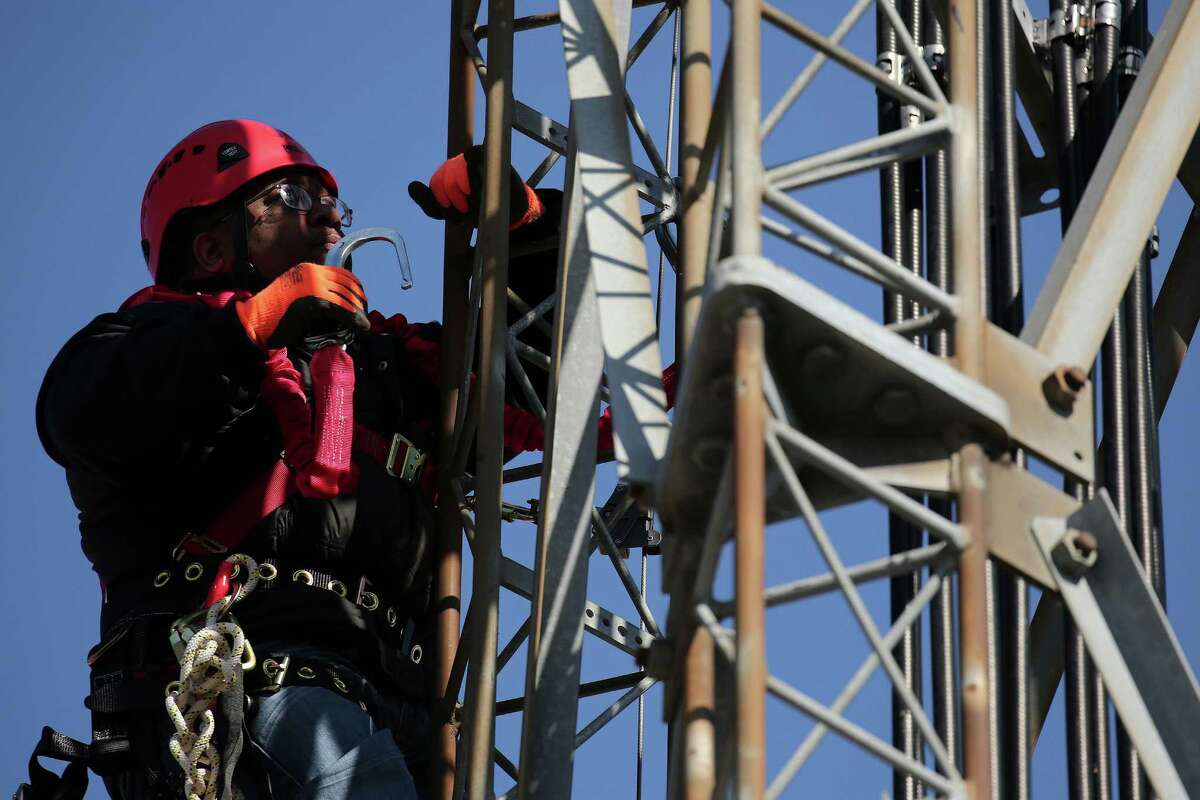 Antonio Crum climbs a cellphone tower while practicing maintenance during a training program in Chicago. ﻿