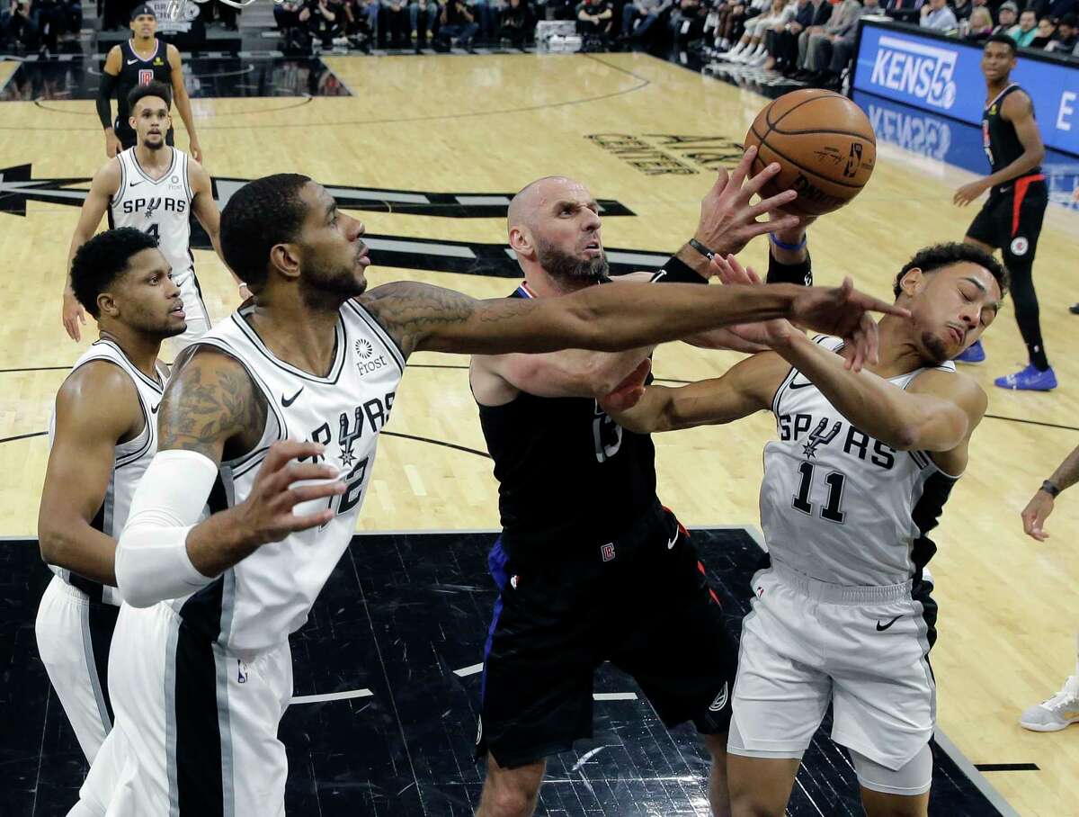 Los Angeles Clippers center Marcin Gortat (13) battles San Antonio Spurs forward LaMarcus Aldridge (12) and guard Bryn Forbes (11) for a rebound during the first half of an NBA basketball game, Thursday, Dec. 13, 2018, in San Antonio. (AP Photo/Eric Gay)
