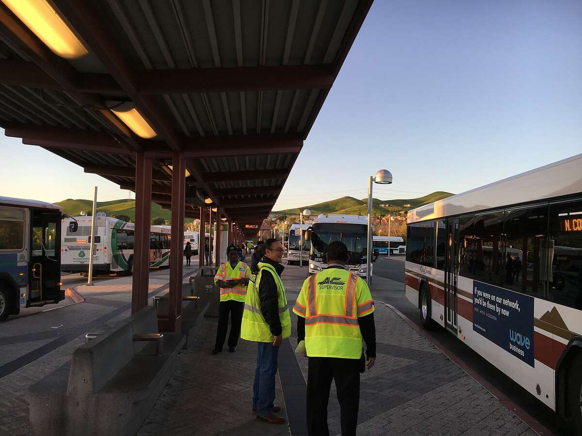 BART workers stand ready to guide commuters to a bus-bridge as the transit agency heads into its second day of delays and halted service due to a track problem in the East Bay.