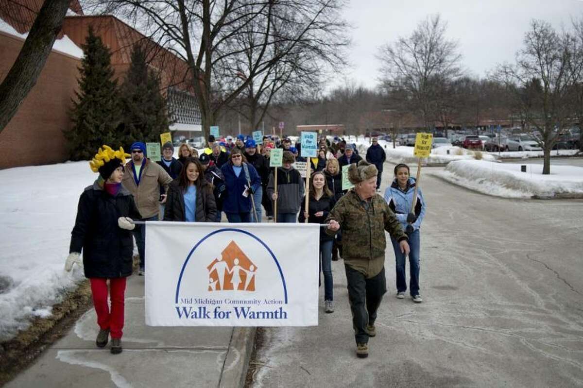 Kiwassee Kiwanis Club members Diane Stevens, left, and Millard Kent, right, hold a sign and lead the crowd at the start of the Mid Michigan Community Action Agency's Walk for Warmth in this 2014 file photo. This year marks the 25th anniversary of the Walk for Warmth.