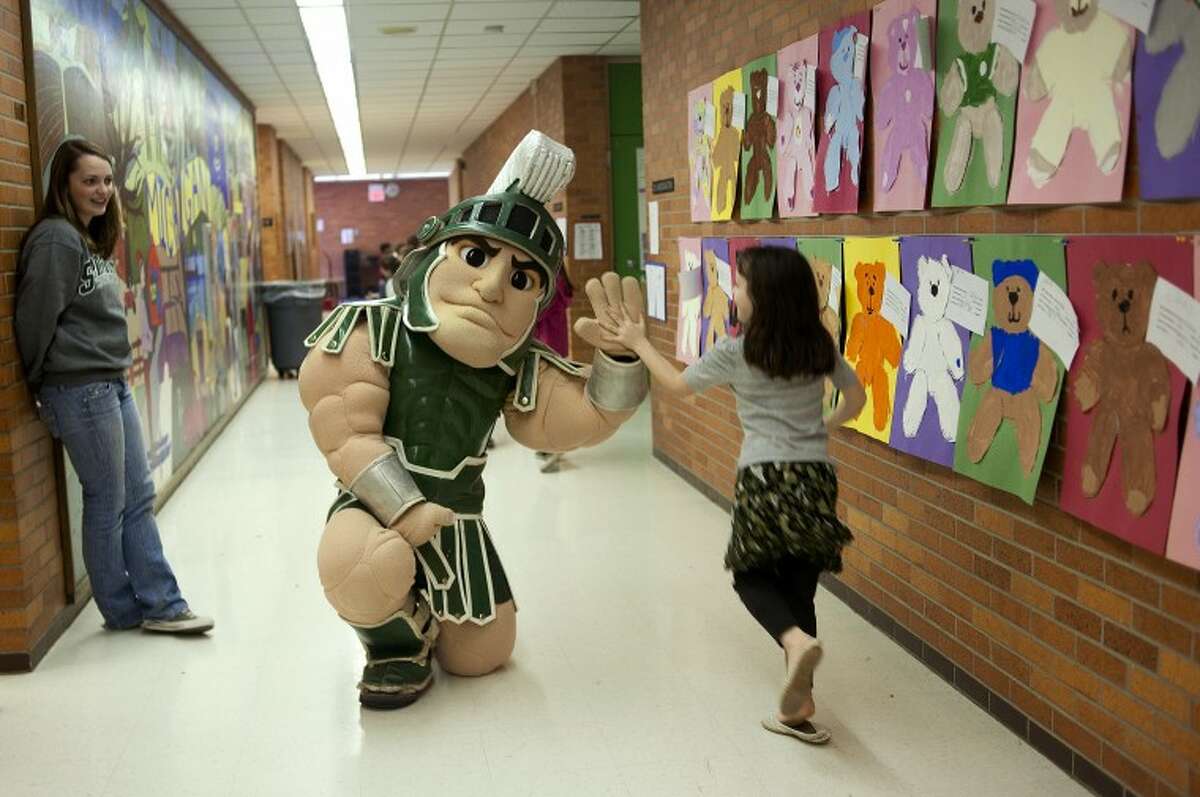 NEIL BLAKE | nblake@mdn.netSparty, the mascot at Michigan State University, high fives a student at Woodcrest Elementary on Tuesday as MSU sophomore Erin Lucian looks on. Sparty made the rounds to Chestnut Hill, Plymouth and Woodcrest elementary schools promoting reading and leading students in cheers of "Go green, go white!"