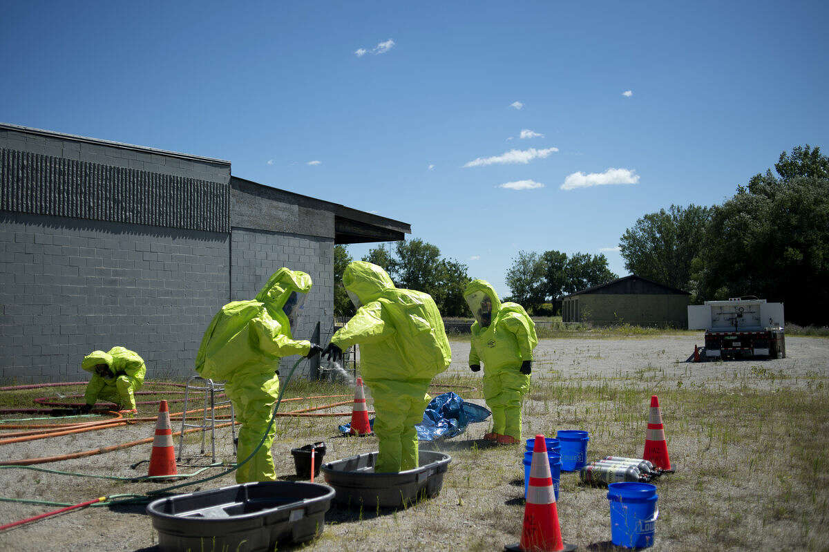 Members of the Midland Fire Department decontaminate their fully incapsulated HAZMAT suits after investigating a hazardous material leak during a training exercise on Thursday.