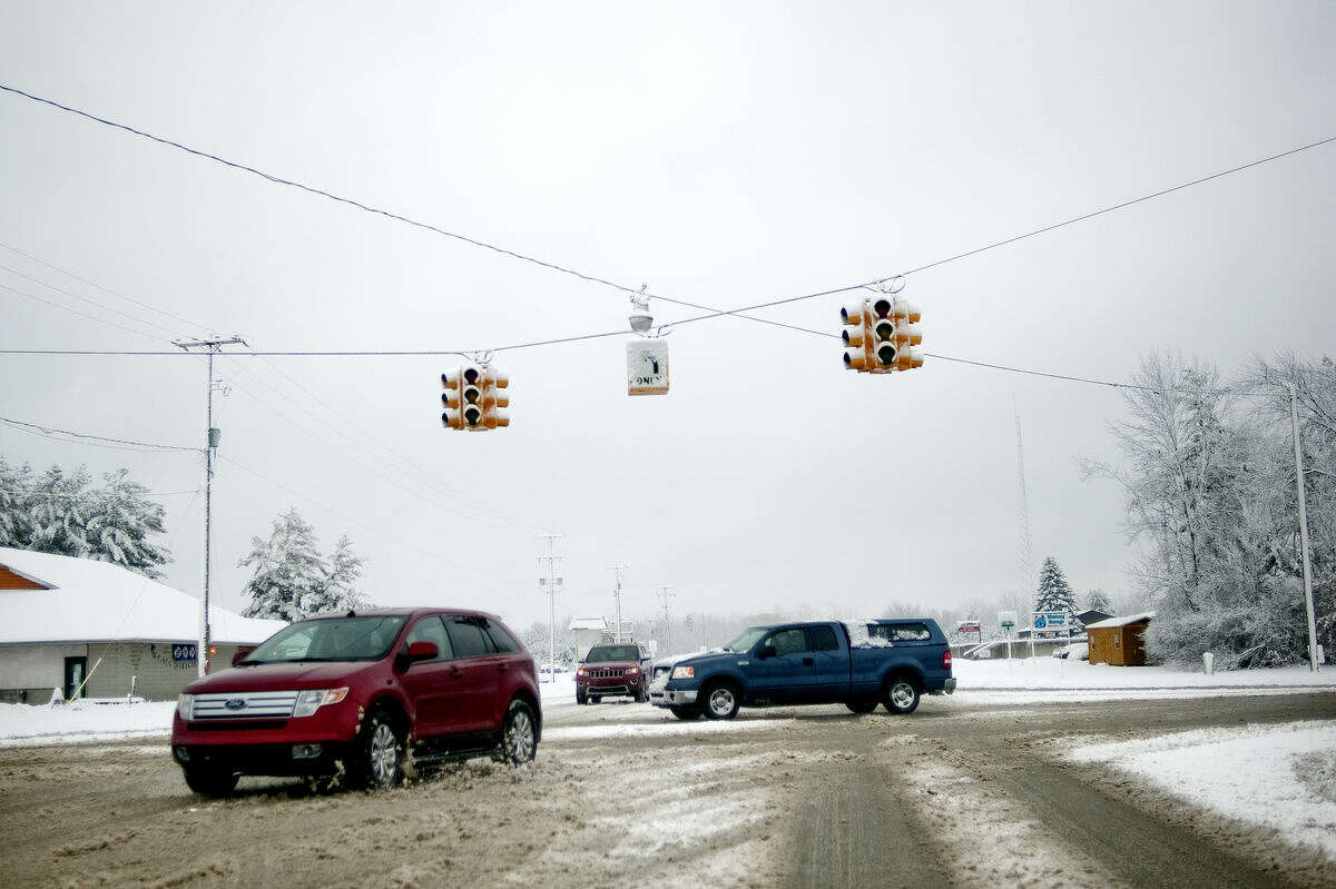 Vehicles move slowly through the intersection of Saginaw and Meridian roads in Sanford on Sunday after a snow storm knocked out power to the traffic lights.