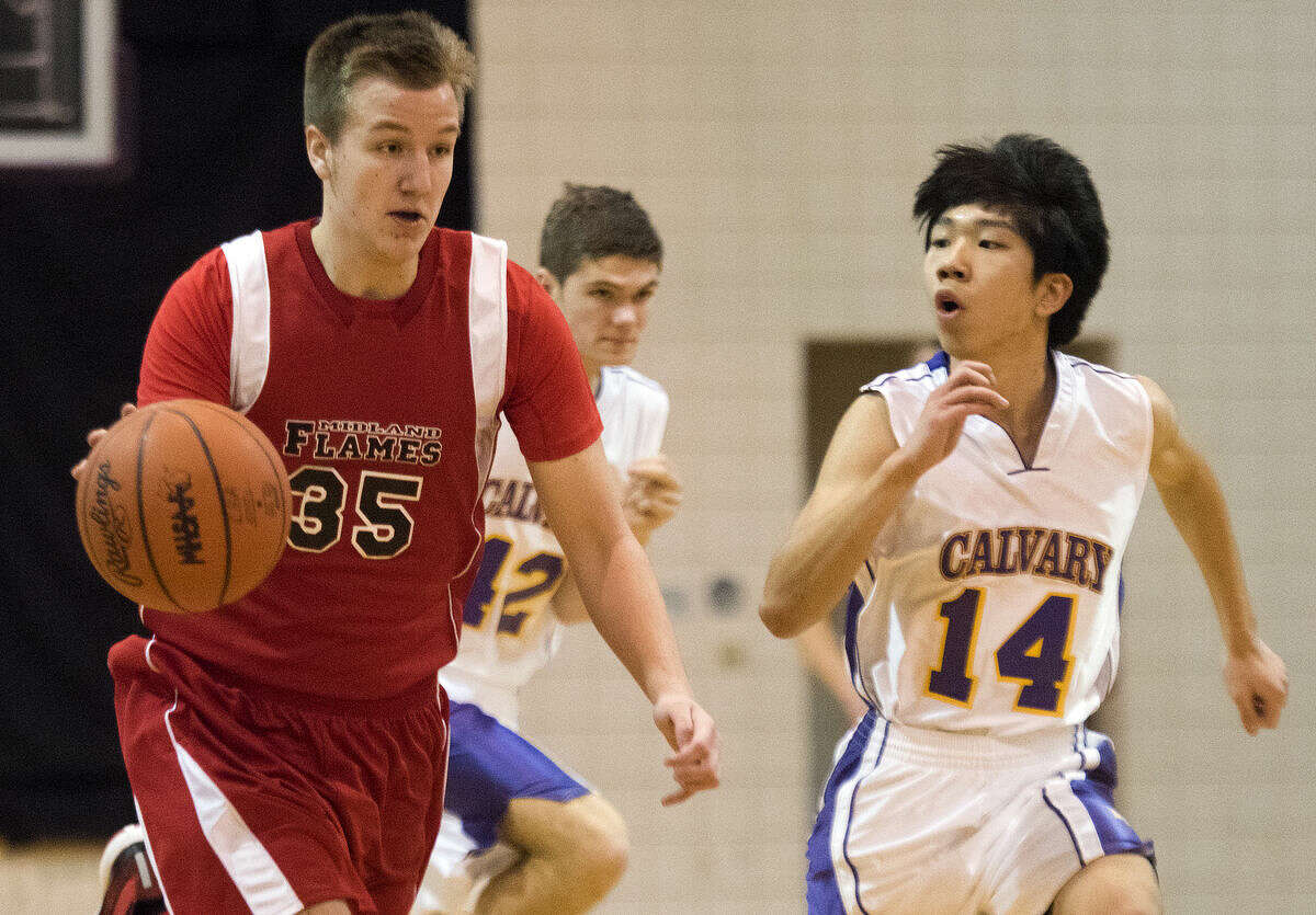 The Flames' Nate Winterstein dribbles down the court, pursued by Calvary's Justin Kim at Calvary Baptist Academy in Midland on Tuesday.