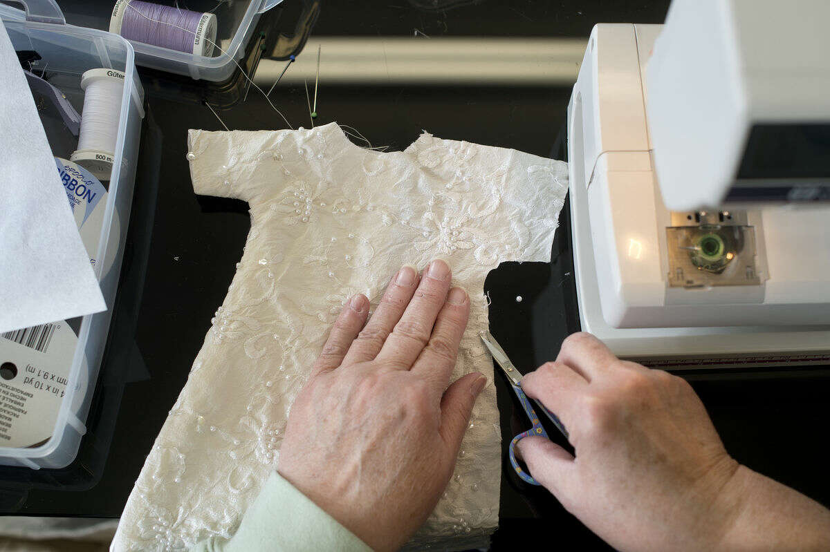 Linda Stechschulte of Owosso trims stray threads on a burial gown made from a donated wedding dress at Miles of Stitches in Merrill Thursday afternoon. "I worked as an OB nurse and I had firsthand experience with what families have to go through," Stechschulte said. "Since I'm retired I thought this was something nice that I could do."