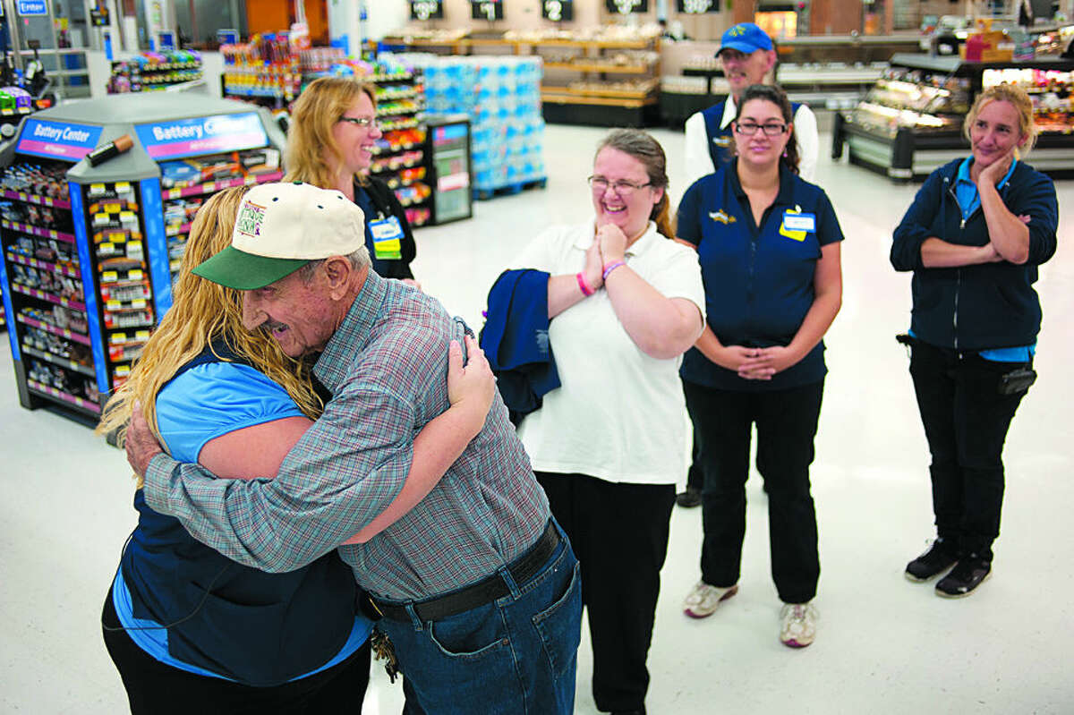 BRITTNEY LOHMILLER | blohmiller@mdn.net Walmart employee Malissa Gillespie, left, gives Cecil Rydman of Beaverton a hug and wished him a happy birthday Friday morning. Walmart employees gathered inside the Midland store to celebrate Cecil's upcoming 100th birthday by giving him a card and cake. Rydman has been shopping at the store since its' opening.