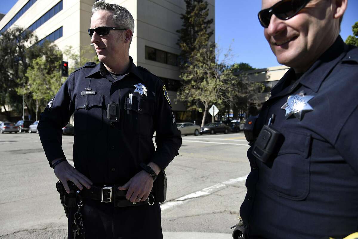 Officers Mike Cooper, left, and officer John Hargraves talk with fellow officers in front of the Oakland Police Department Headquarters in Oakland, CA Thursday, March 17, 2016.