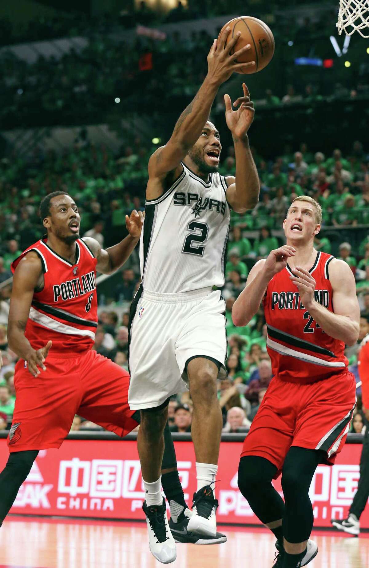 San Antonio Spurs' Kawhi Leonard shoots between Portland Trail Blazers' Al-Farouq Aminu (left) and Mason Plumlee during second half action Thursday March 17, 2016 at the AT&T Center. The Spurs won 118-110.