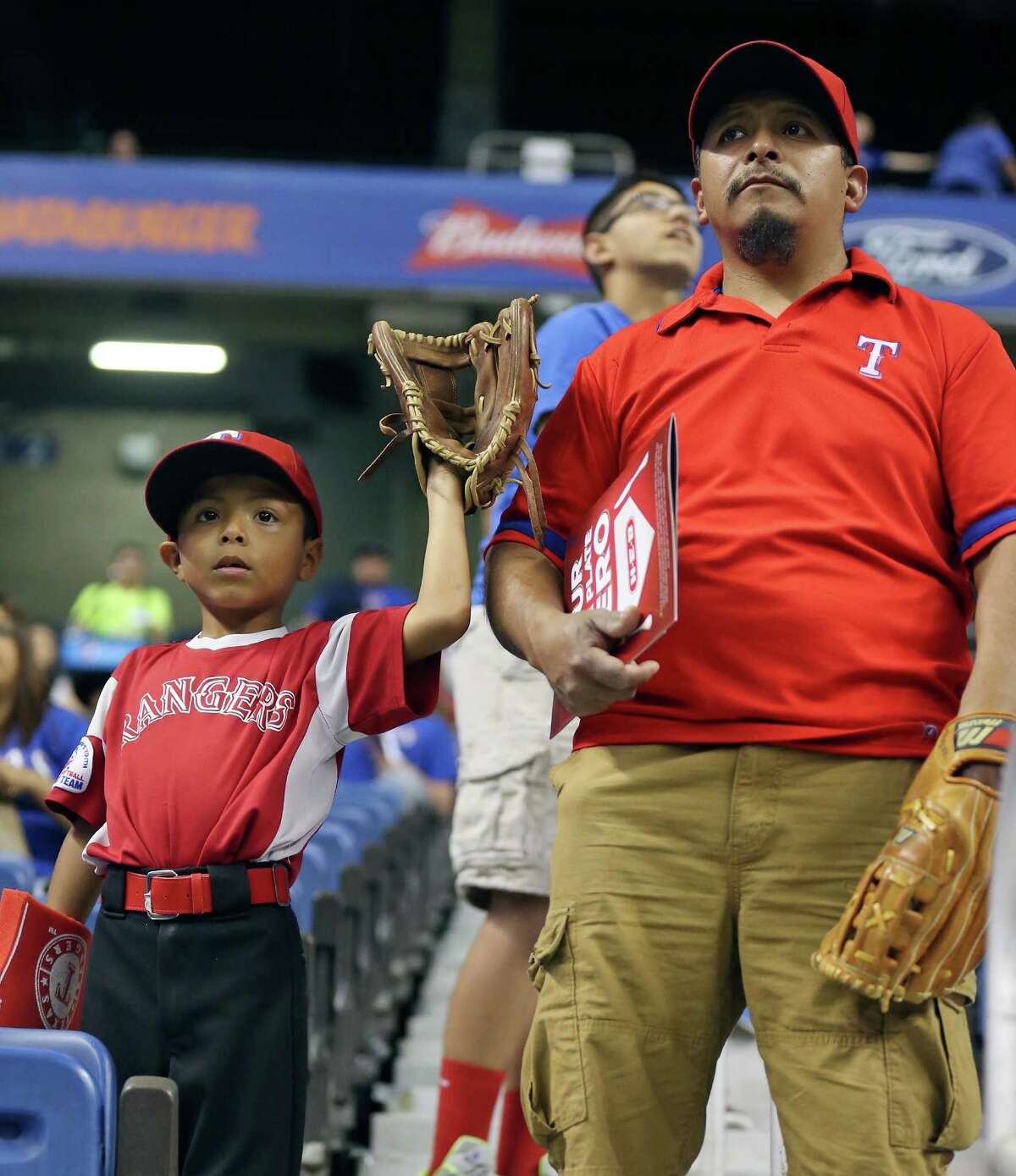 Texas Rangers fans Alfonso Olvera Jr, 7, (left) and his dad Alfonso Olvera watch batting practice before the Rangers and Kansas City Royals Big League Weekend spring exhibition baseball game Friday March 18, 2016 at the Alamodome.