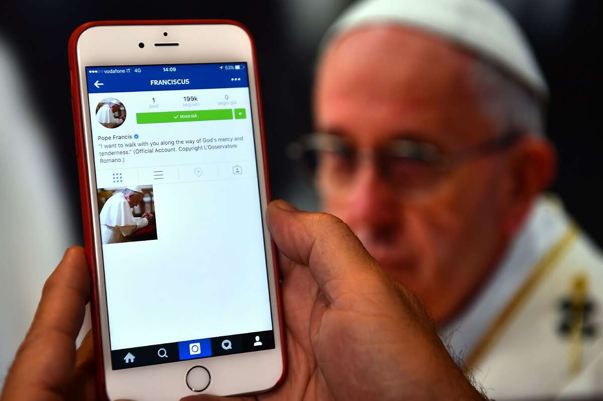 A man looks at the Instagram account of Pope Francis (Franciscus) on March 19, 2016 in Rome. The date for the pontiff's debut on the celebrity-dominated social medium was chosen by the 79-year-old himself as it marks the third anniversary of his inauguration as the leader of the world's 1.2 billion Catholics.