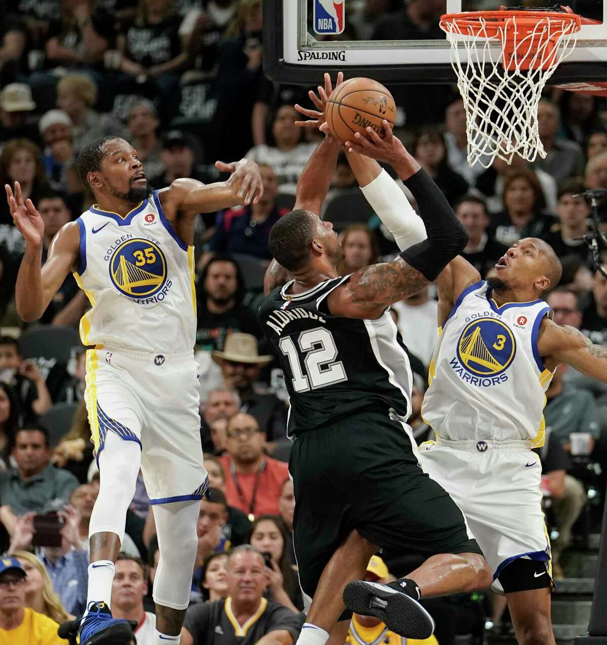 San Antonio Spurs' LaMarcus Aldridge (12) shoots against Golden State Warriors' David West (3) and Kevin Durant during the first half of Game 4 of a first-round NBA basketball playoff series in San Antonio, Sunday, April 22, 2018, in San Antonio. (AP Photo/Darren Abate)