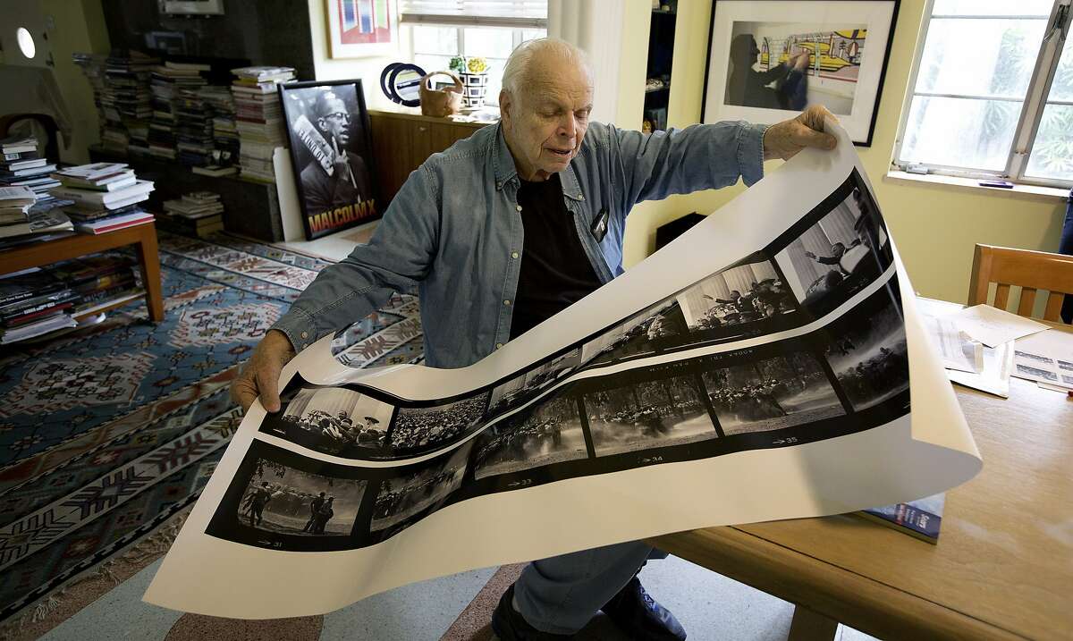 In this Jan. 9, 2014 photo, Bob Adelman unwraps and examines an enlarged contact sheet of photos from his days working with the civil rights movement, in his Miami Beach, Fla. home. His work will be seen in an exhibition that commemorates the 50th Anniversary of the Civil Rights Act of 1964 and features 150 photographs by Adelman, whose work during the civil rights era put him at the forefront of the civil rights movement and led him to produce some of the most iconic photographs of the period. Between 1963 and 1968, Adelman was a photographer for civil rights organizations including the Congress for Racial Equality (CORE), the Student Non-Violent Coordinating Committee and NAACP Legal Defense Fund. His work granted him unique access to the movement’s most important events and figures. (AP Photo/J Pat Carter)