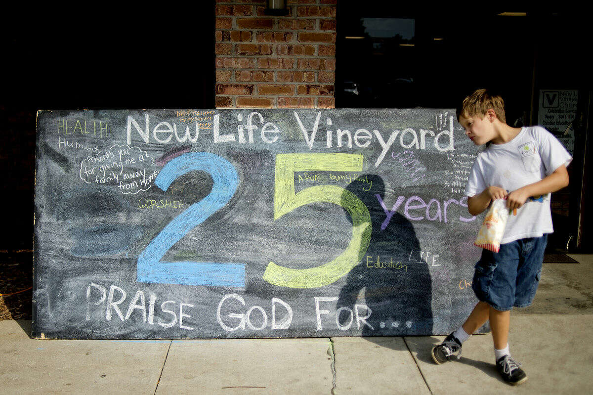 Matthias Francisco, 9, eats popcorn in front of chalk board with messages relating to the 25 years of the church on Saturday during a neighborhood party and 25th anniversary celebration at New Life Vineyard Church in Midland. The free event, which was open to all, featured carnival games, food and live music.