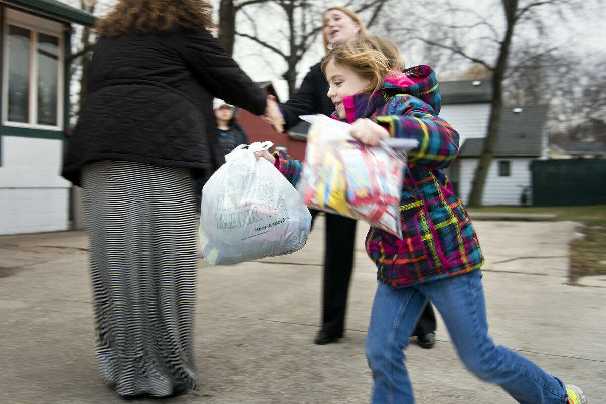 Addie McLaughlin, 7, runs into the Open Door Crisis Shelters and Soup Kitchen, carrying bags of donations. Instead of presents for herself for her Dec. 4 birthday, Addie told her parents she wanted to give presents to those who are less fortunate. The project, dubbed "Addie's Gift," collected two vehicles full of donated food and clothing, as well as $1,212 to be presented to Open Door.