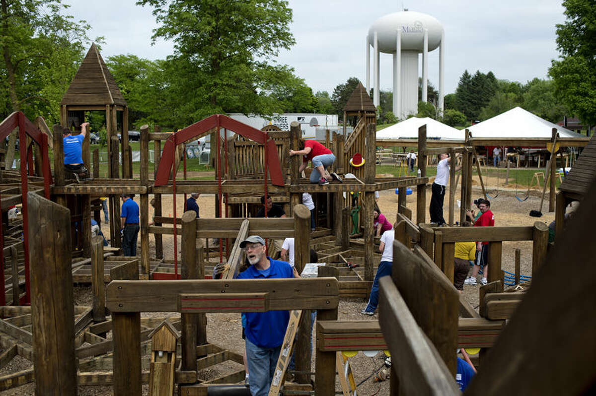 Midland Kiwanis member Earl Soules, center, sands the wood at the FunZone playground while volunteering at Plymouth Park in June. The playground was remodeled with new play equipment, a new picket fence and more.