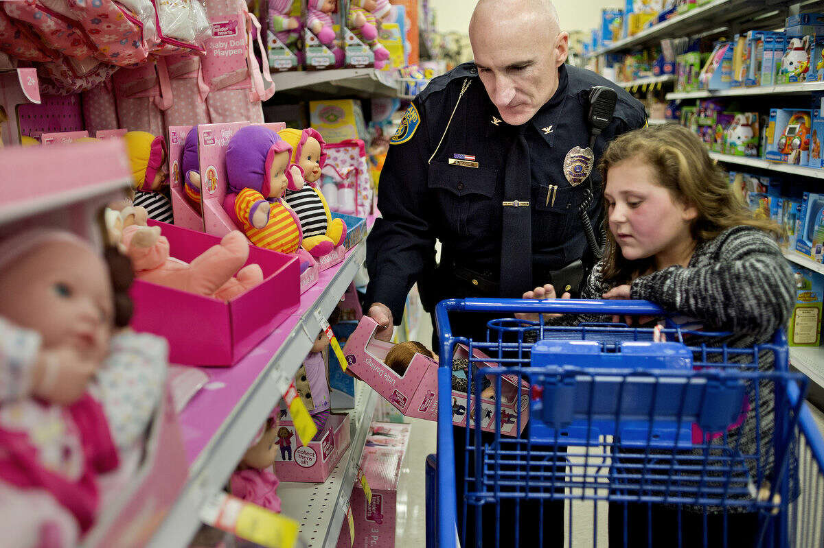 Midland Police Chief Cliff Block, left, helps McKenna Herkel, 7, pick out a doll for her cousin during the Shop with a Hero event on Monday at the Midland Meijer. Herkel picked out items for family members as well as for herself. The event, a partnership involving Meijer, the Salvation Army and local emergency personnel, teams up underprivileged children with a heroes to shop with $100 gift cards.