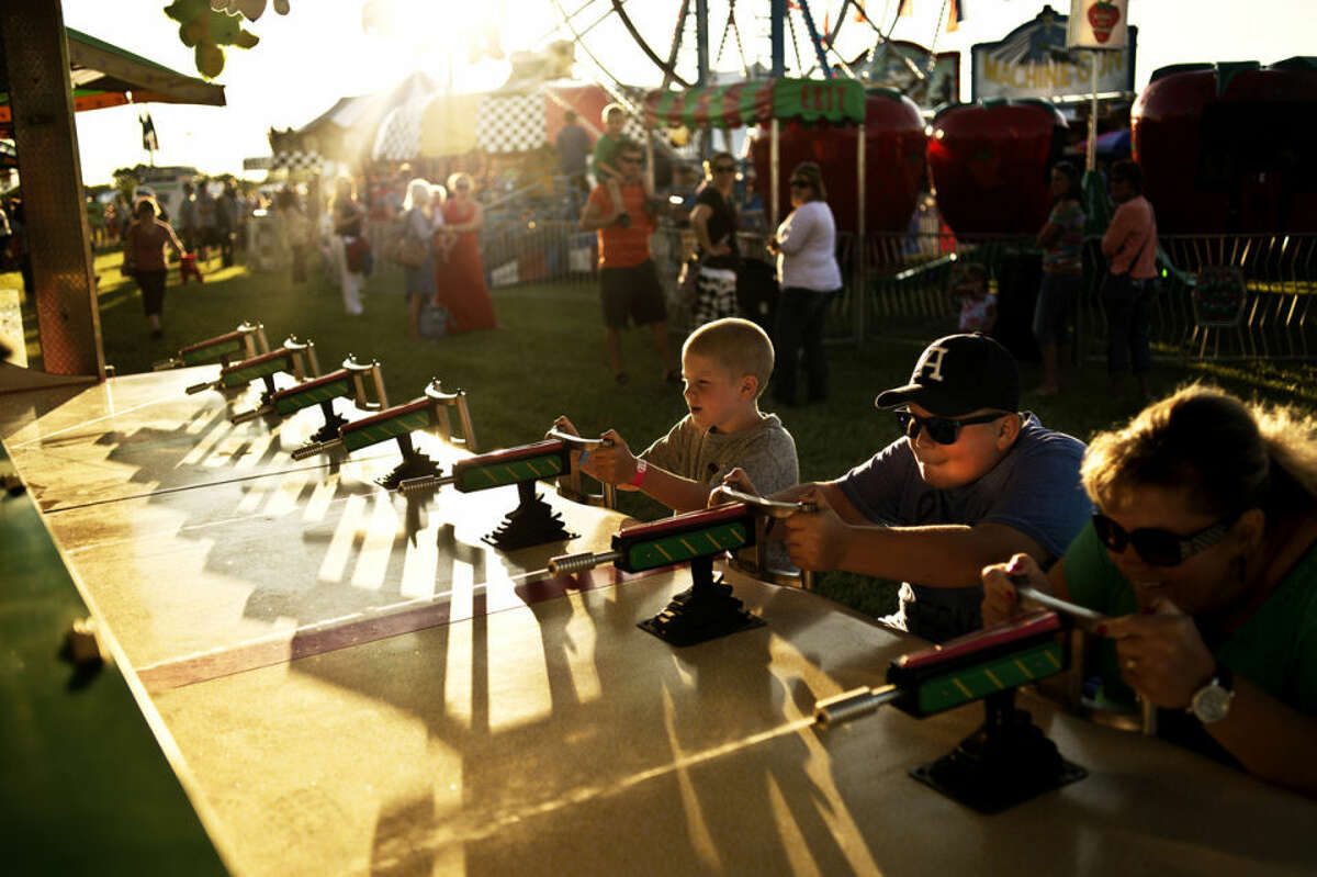 Casey Helmreich, of Linwood, far right, places the "Water Game" with her two sons Brett, 12, and Brendan, 7, Thursday evening during the Auburn Cornfest. The event continues throughout the weekend with carnival games, food and live entertainment.
