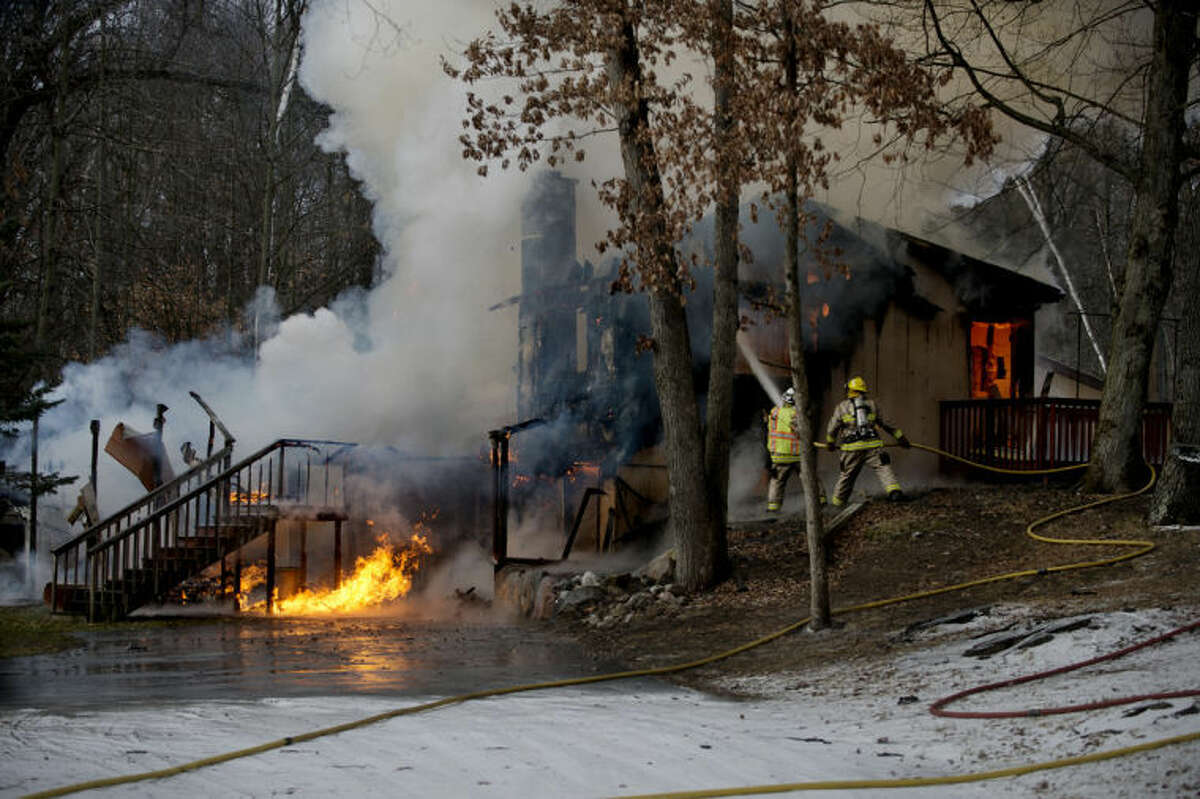 NEIL BLAKE | nblake@mdn.netFirefighters battle a blaze at a home on Huckleberry Road between 11 Mile Road and North Castor Road on Tuesday.