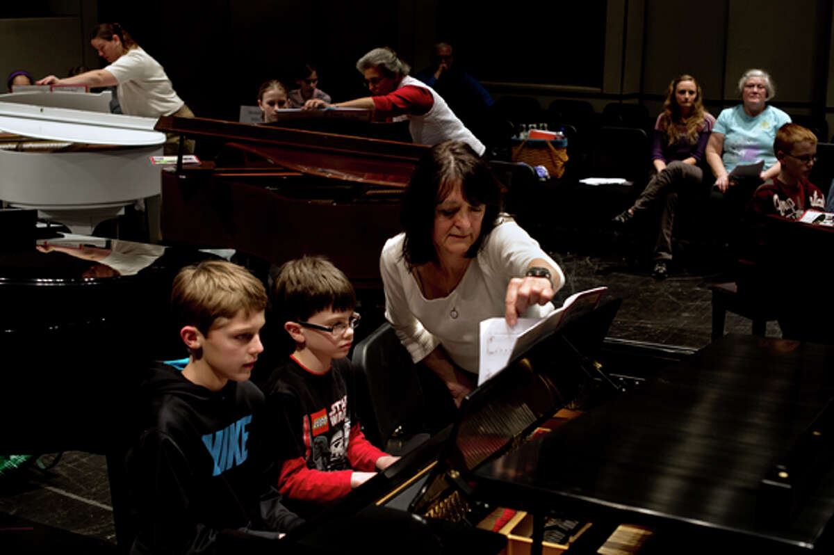 Mary Ann Anschutz, of Midland, turns over a page as Thomas Metcalf, 8, center, and Jack Miller, 10, practice their four-handed duet of The Yellow Rose of Texas Friday evening during the recital practice for KeyboardFest at the Midland Center for the Arts. Anschutz has taught piano for 40 years and been involved with KeyboardFest since the first recital, 23 years ago. Presented by the Midland Music Teachers' Association, the official recital starts at 7 p.m. Saturday and features numerous students playing the piano simultaneously.