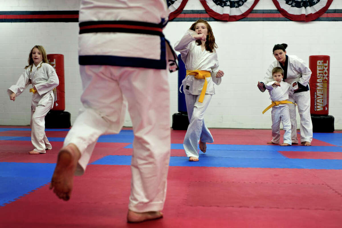 SEAN PROCTOR | sproctor@mdn.netAs Master James Hixenbaugh of Davison, foreground, guides McKenna, left, and Ryleigh Kramer, center, of Midland, through Tang Soo Do moves Summer Tanner, 21, right, of Davison, helps Caleb Haney practice the proper motions during the yellow belt class at the Professional Karate School of America on North Saginaw Road.