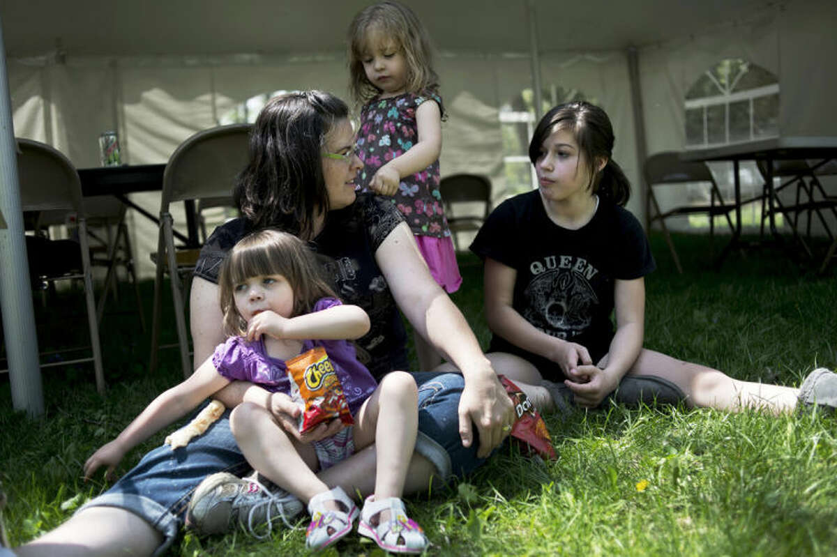 SEAN PROCTOR | sproctor@mdn.netFrom left, Autumn, 3, Holly, Lillie, 3, and Grace Stillwagon, 11, sit in the grass in the empty lot adjacent to their new home while volunteers work on construction efforts for Habitat for Humanity. Holly said she couldn't find a sitter for the day, so she stayed home for the day, as opposed to being on site helping with construction.