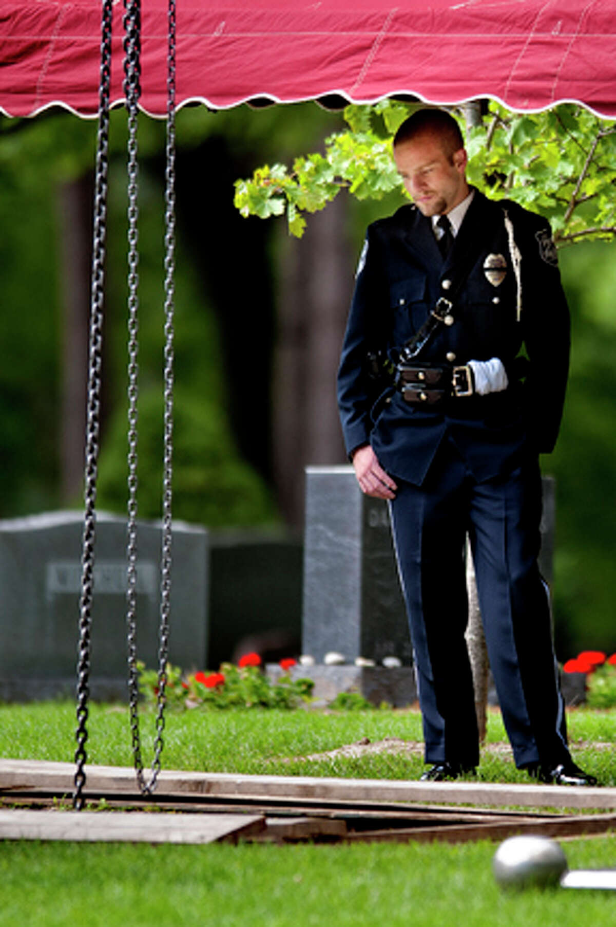 Rapid City Police Officer Cade Bloomenrader looks on as the lid of the burial vault is put in place after the funeral of Rapid City Police Officer J. Ryan McCandless, Thursday, Aug. 11, 2011, at the Midland Cemetery in Midland Mich. Bloomenrader was a good friend of McCandless, who was killed in the line of duty last week in South Dakota. McCandless, a 2001 H.H. Dow High graduate, is the son of retired Midland County Undersheriff James McCandless.