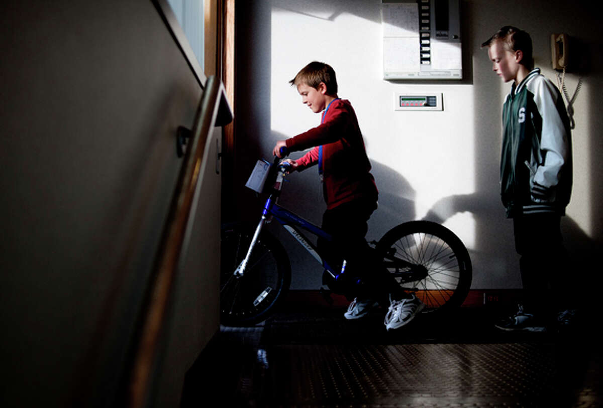 Carl Fodo, 8, wheels his new bike out of the Dow Chemical Employees’ Credit Union as his brother Austin, 9, follows behind on Monday.Carl and 29 other kids were given bikes that 140 Credit Union employees put together, with the help of Brad Alvesteffer and Cody Evans of Ray’s Bike Shop.
