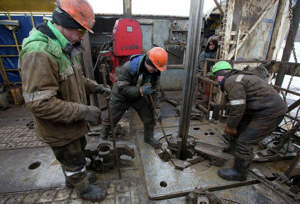 Oil workers adjust a pipe section at the turntable on an oil derrick in an oilfield in the village of Otrada, Russia. After a promising start on keeping its pledge to cut production, Russian production is now just over halfway to the reduction Moscow promised. Compliance from the 11 non-OPEC participants — estimated at just 64 percent in February — will come under scrutiny at a ministerial meeting in Kuwait City on Sunday.