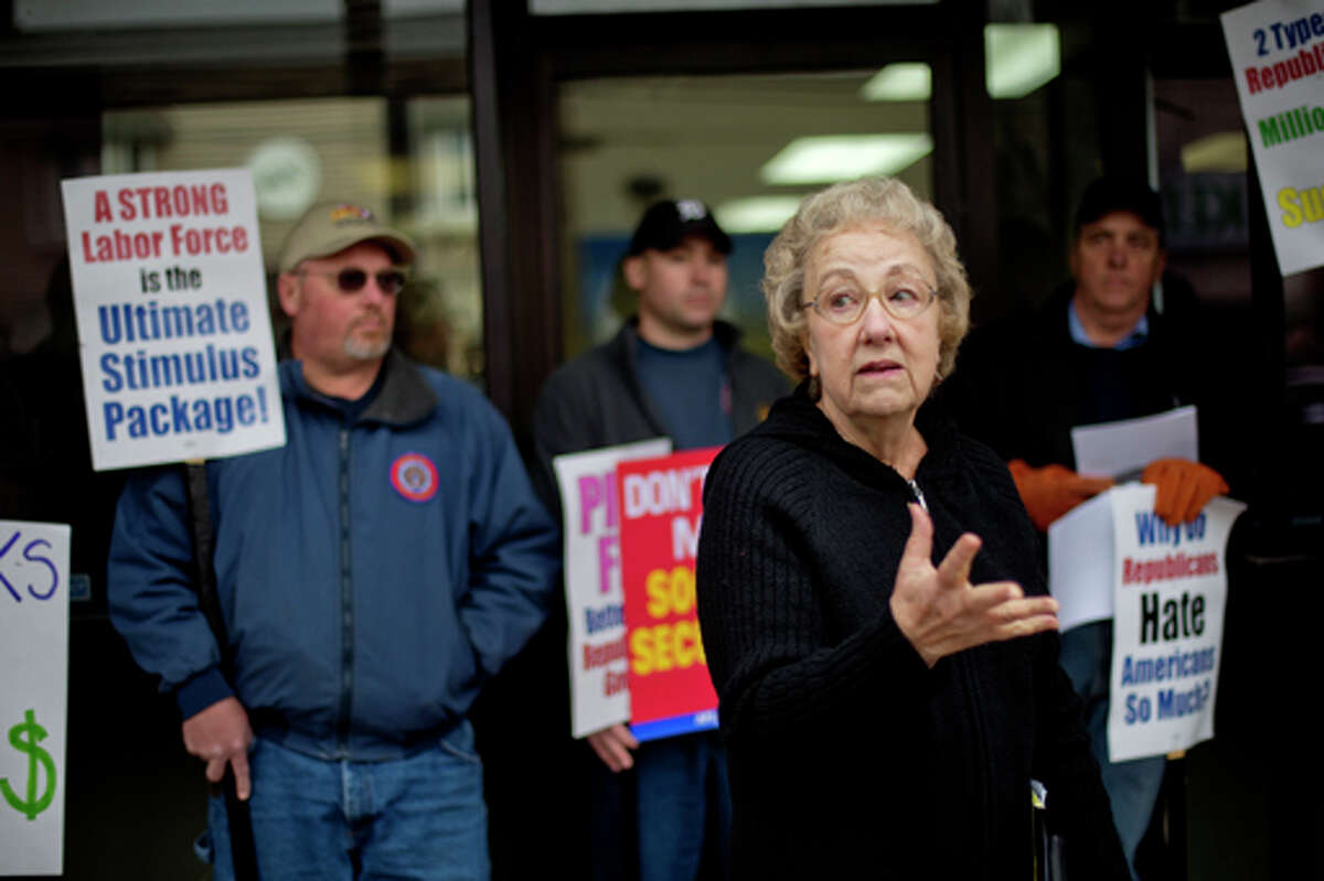 NICK KING | nking@mdn.net Margie Mitchell, executive director of the Michigan Universal Health Care Access Network, speaks during a demonstration against the Ryan budget plan Thursday outside Congressman Dave Camp's Midland office.