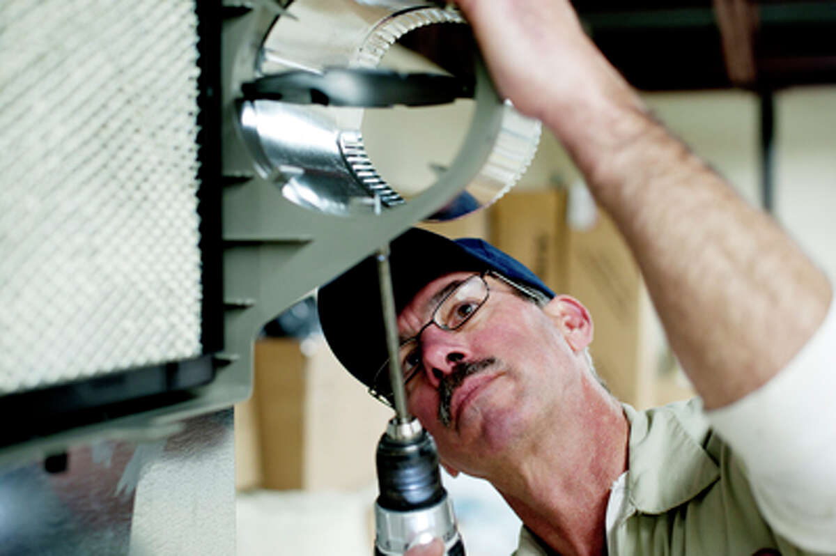 Reliable Heating and Cooling employee Pete Campau, of Sanford, screws in duct work while installing a humidifier at Reliable Heating and Cooling in Midland for the office area.
